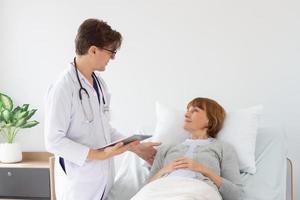 male doctor consulting senior old patient. Professional physician wearing white coat talking to mature woman. photo