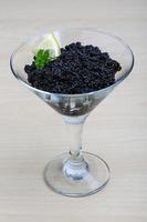 Black caviar in a bowl on wooden background photo