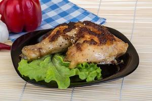 muslo de pollo asado en el plato y fondo de madera foto