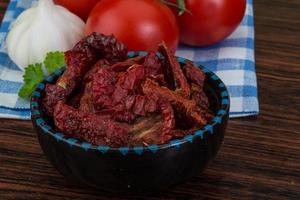 Dried tomtoes in a bowl on wooden background photo