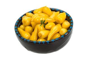 Yellow marinated pepper in a bowl on white background photo