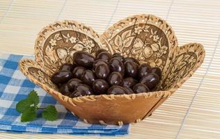 Almond in chocolate in a basket on wooden background photo