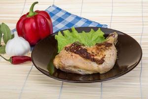 Roasted chicken leg on the plate and wooden background photo