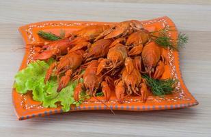 Boiled crayfish on the plate and wooden background photo