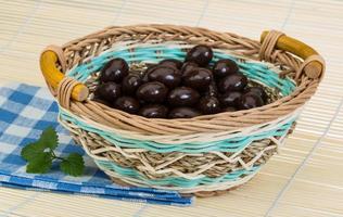 almendra en chocolate en una canasta sobre fondo de madera foto