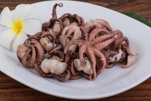 Boiled octopus on the plate and wooden background photo