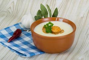 Cheese soup with croutons in a bowl on wooden background photo