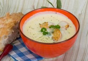 Cheese soup with croutons in a bowl on wooden background photo