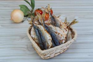 Dry fish in a basket on wooden background photo