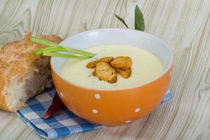 Cheese soup with croutons in a bowl on wooden background photo