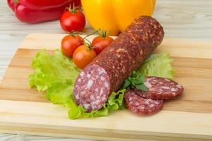 Salami on wooden board and wooden background photo