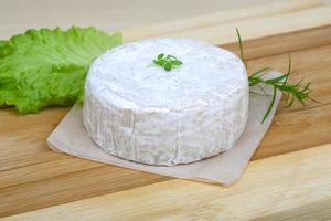 Brie cheese on wooden board and wooden background photo