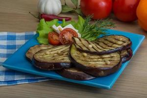 berenjena a la parrilla en el plato y fondo de madera foto