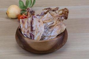 Dried squid in a bowl on wooden background photo