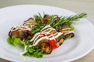 Aubergine roll on the plate and wooden background photo