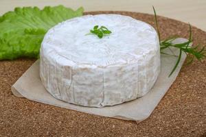 Brie cheese on wooden board and wooden background photo