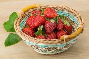 Fresh strawberry in a basket on wooden background photo