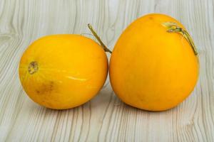 Small yellow melon on wooden background photo