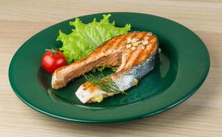 Grilled salmon steak on the plate and wooden background photo