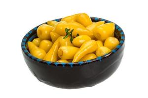 Yellow marinated pepper in a bowl on white background photo