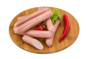 Sausages on wooden board and white background photo