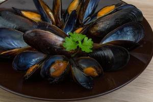 mejillones en el plato y fondo de madera foto