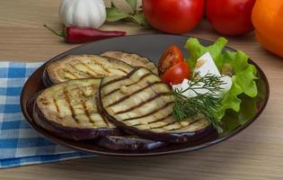 berenjena a la parrilla en el plato y fondo de madera foto