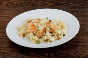 Fried rice with prawns on the plate and wooden background photo