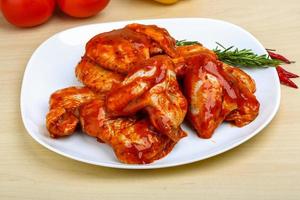 Chicken wings on the plate and wooden background photo