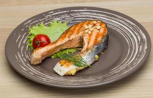 Grilled salmon steak on the plate and wooden background photo