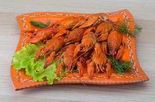 Boiled crayfish on the plate and wooden background photo