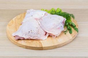 Raw chicken thighs on wooden board and wooden background photo