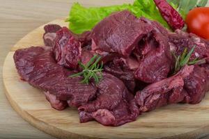 Raw venison on wooden board and wooden background photo