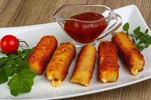 Cheese sticks on the plate and wooden background photo