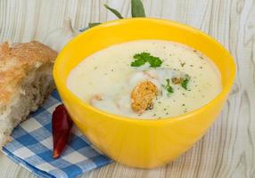 Cheese soup with croutons in a bowl on wooden background photo