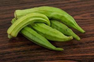 Okra vegetables on wooden background photo