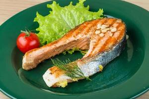 Grilled salmon steak on the plate and wooden background photo
