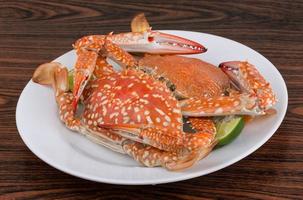 Boiled crabs on the plate and wooden background photo