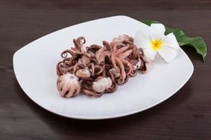 Boiled octopus on the plate and wooden background photo