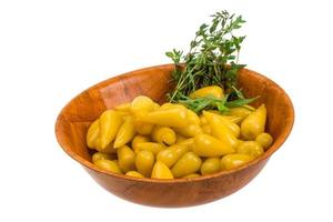 Yellow marinated pepper in a bowl on white background photo