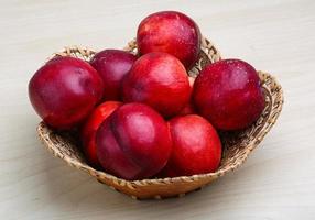 Nectarines in a basket on wooden background photo