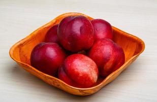 Nectarines in a bowl on wooden background photo