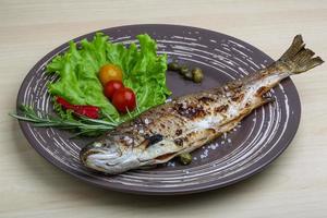 Grilled trout on the plate and wooden background photo
