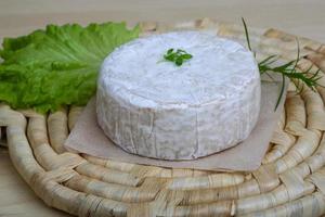 Brie cheese on wooden board and white background photo