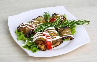 Aubergine roll on the plate and wooden background photo