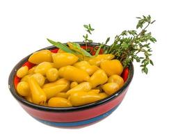 Yellow marinated pepper in a bowl on white background photo