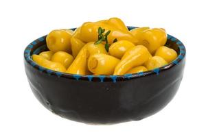 Yellow marinated pepper in a bowl on white background photo