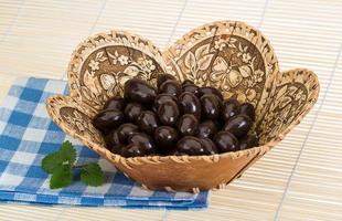 Almond in chocolate in a basket on wooden background photo