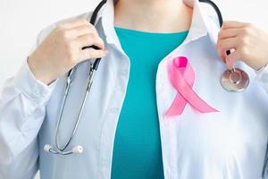 Woman doctor in medical white uniform with pink ribbon. Breast Cancer Awareness Month. Women's health care concept. Symbol of hope and support. photo