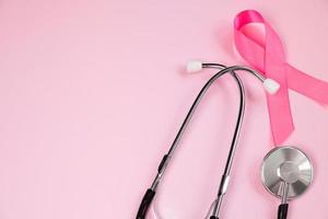 Pink ribbon and stethoscope on colored background. Breast Cancer Awareness Month. Women's health care concept. Symbol of fight against oncology. photo